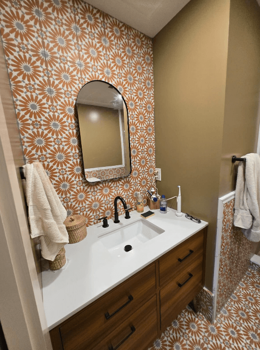 Bathroom vanity with patterned tile backsplash and round mirror in Potomac MD