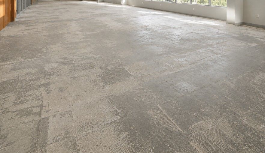 Commercial office flooring before Shaw carpet tile installation with exposed concrete substrate and old adhesive marks