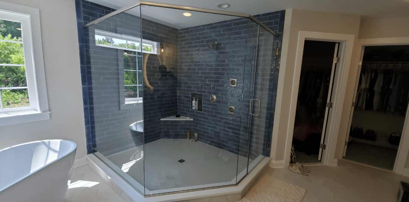 Modern bathroom with glass walk-in shower, blue subway tile, built-in bench, and freestanding soaking tub
