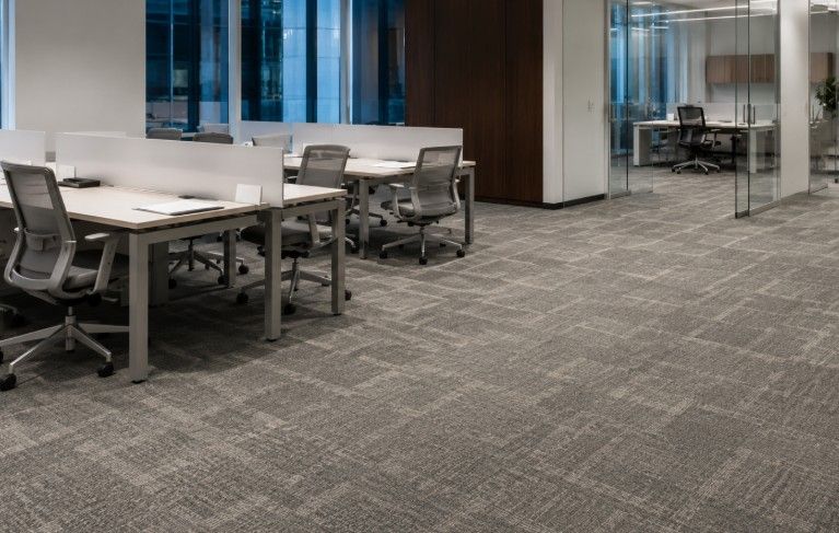 Finished Shaw commercial carpet tile installation in an open office with workstations, rolling chairs, and glass offices